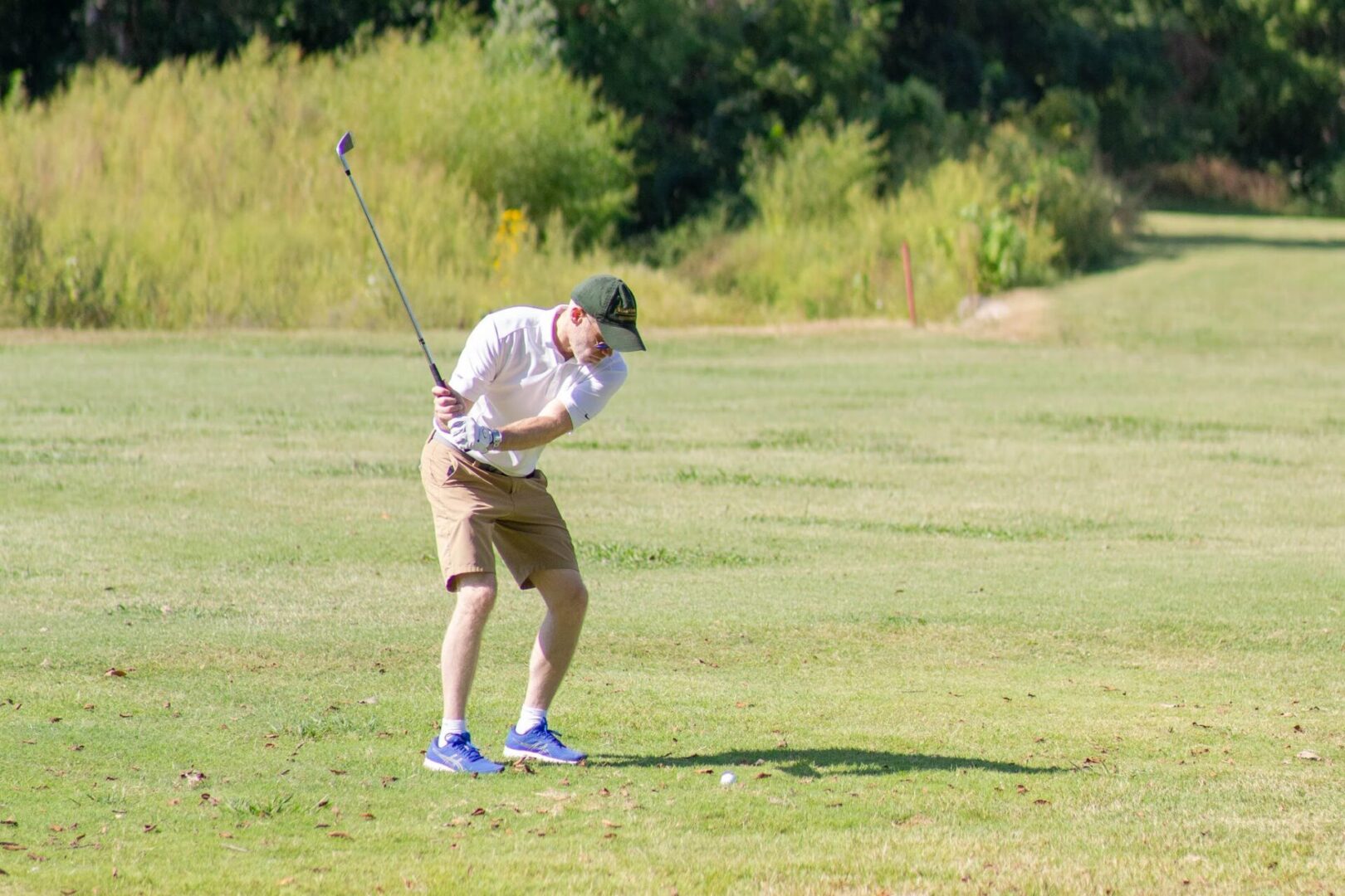 A man swinging at the golf ball on a course.