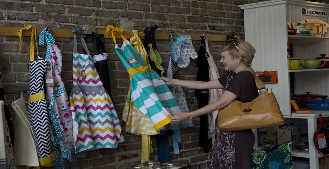 A woman looking at dresses hanging on the wall.