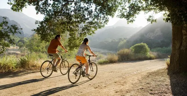 Two people riding bikes on a dirt road.