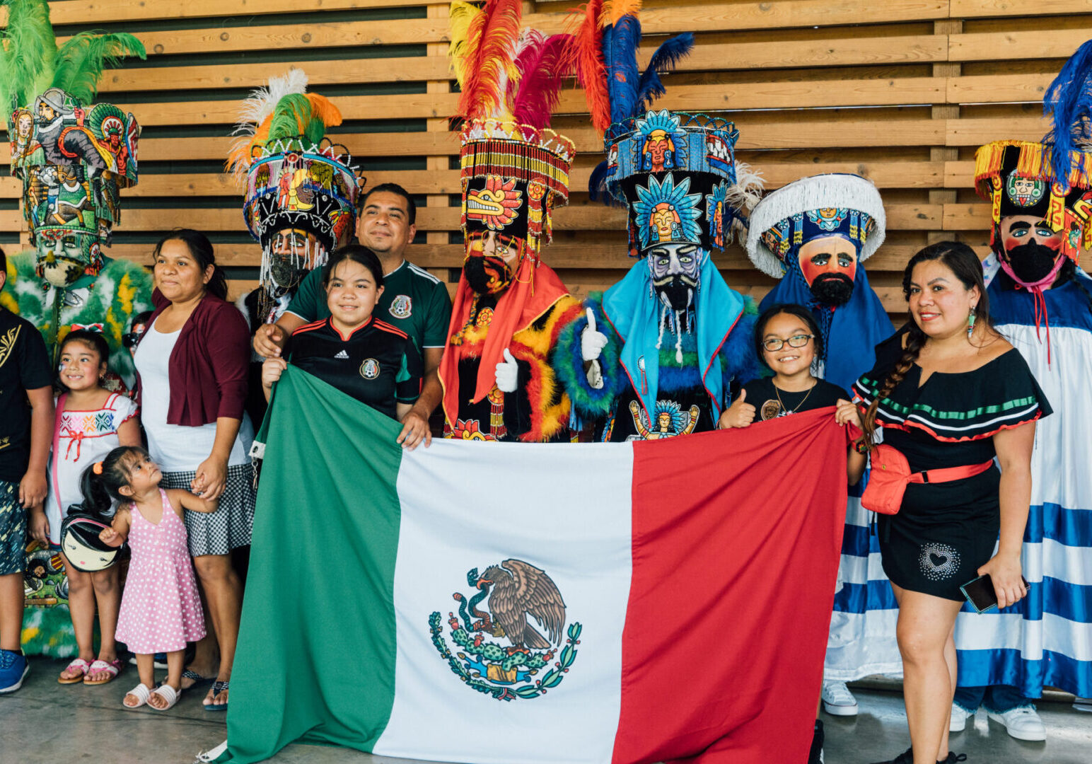 A group of people in costumes holding an mexican flag.